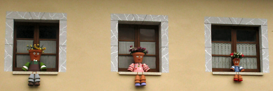 Three Little dolls made from clay pots sitting in windows