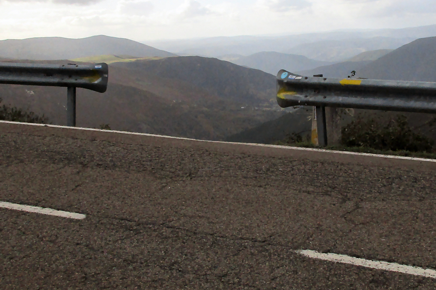 Looking at a gap in the road guardrails where it looks like the trail goes straight down.