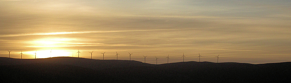 Windmills on a high ridge silhouetted at dawn