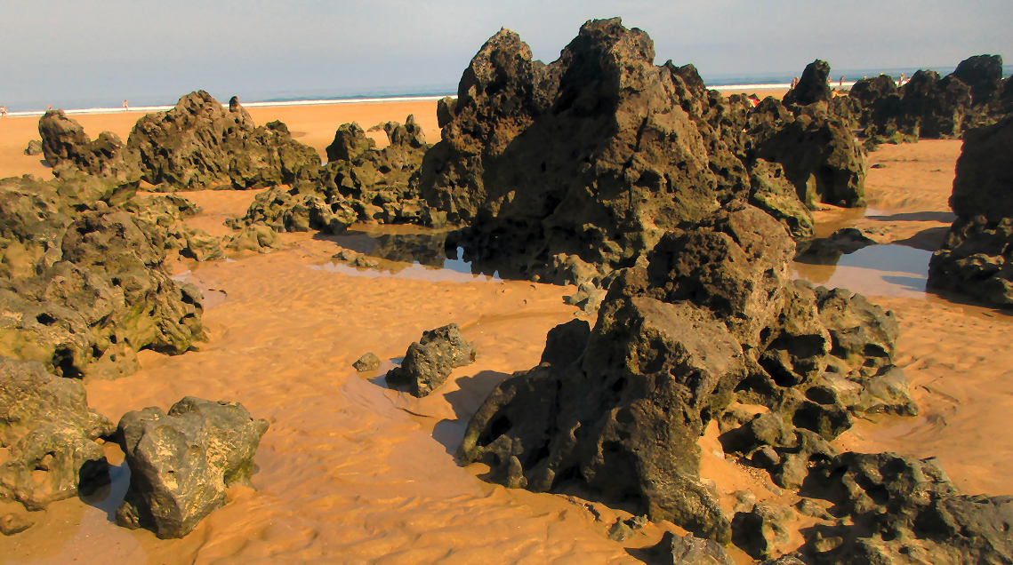 Craggy rocks below the tide line on the beach near Noja, Spain.