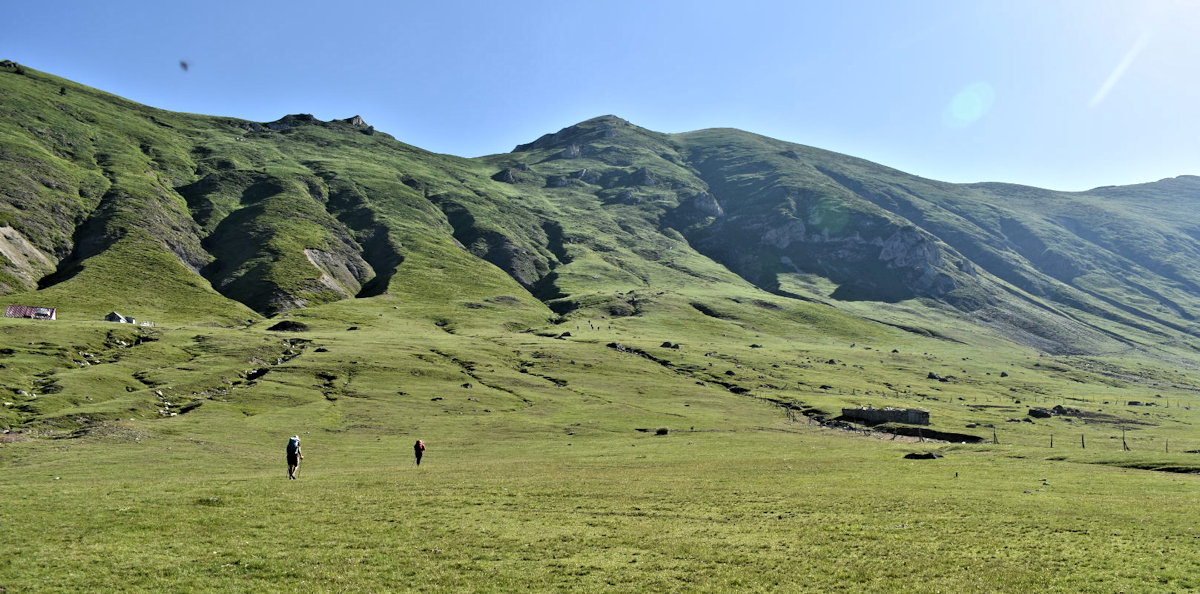 Rebecca and Cathy hiking across a huge meadow pasture on the Peaks of the Balkans trail.