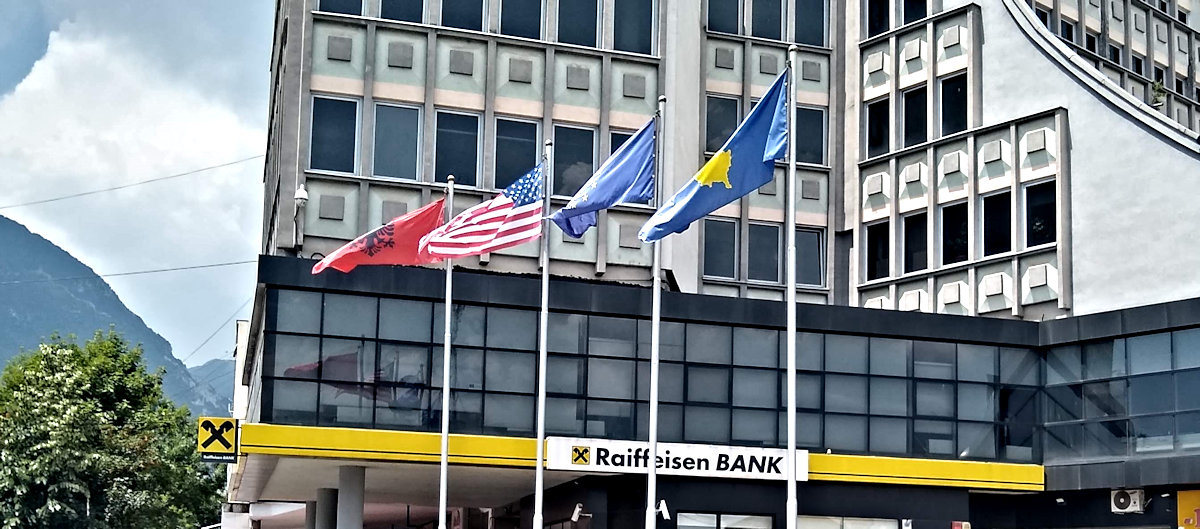 Four flags flying in Peje: Albanian, United States, EU, and Kosovo